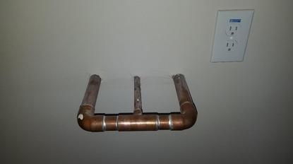 Copper softener loop coming out of a garage wall, next to an outlet